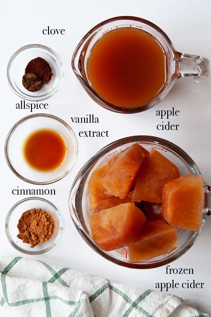 All of the ingredients needed to make apple cider slushie such as frozen apple cider, vanilla extract, allspice, and cinnamon