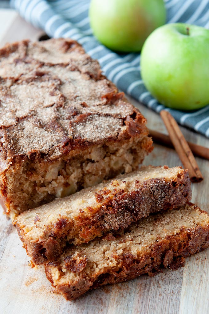 Sliced apple cinnamon bread with cinnamon sticks and Granny Smith apples in the background