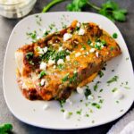 Up close plate of hot easy cheese enchiladas with red sauce, topped with queso fresco and chopped cilantro