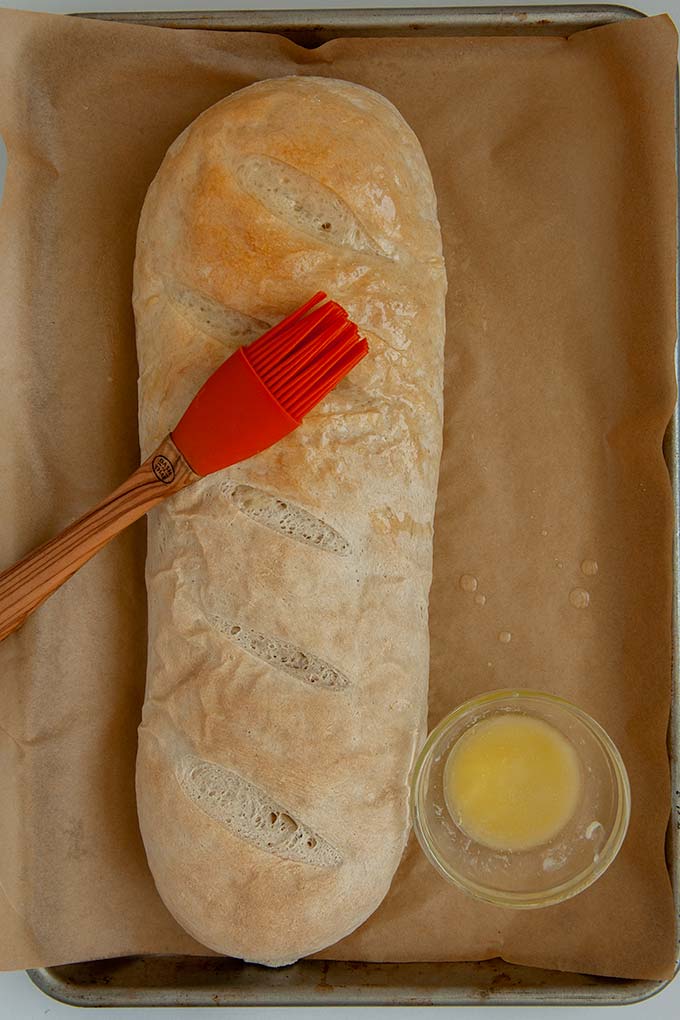 Whole loaf of homemade French Bread slathered in butter
