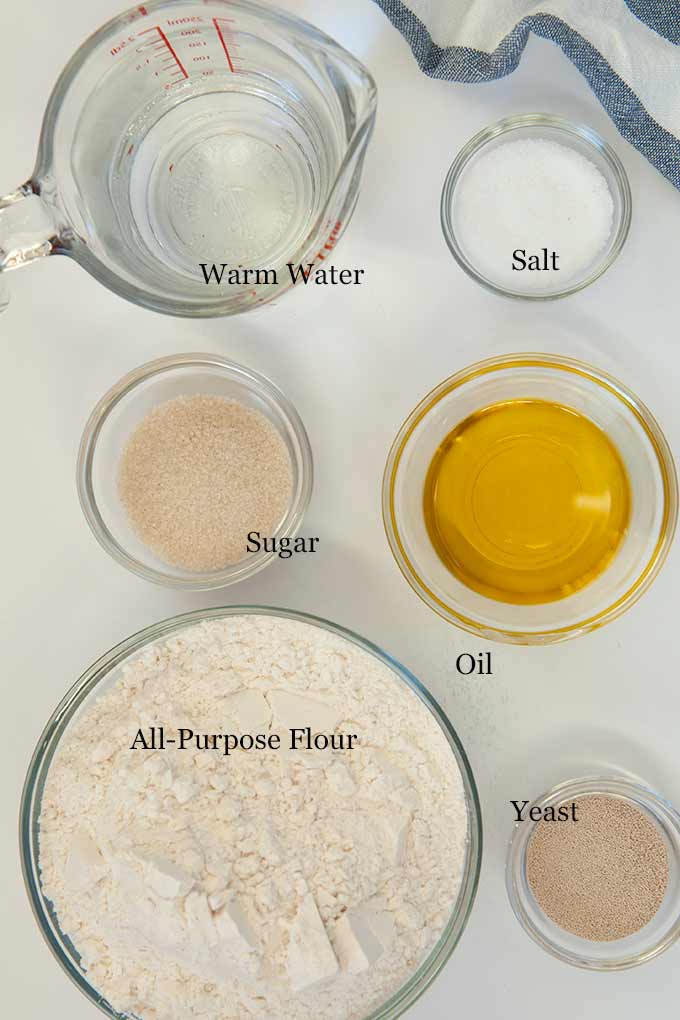 All of the ingredients needed to make homemade French Bread such as flour, oil, salt, sugar, and yeast
