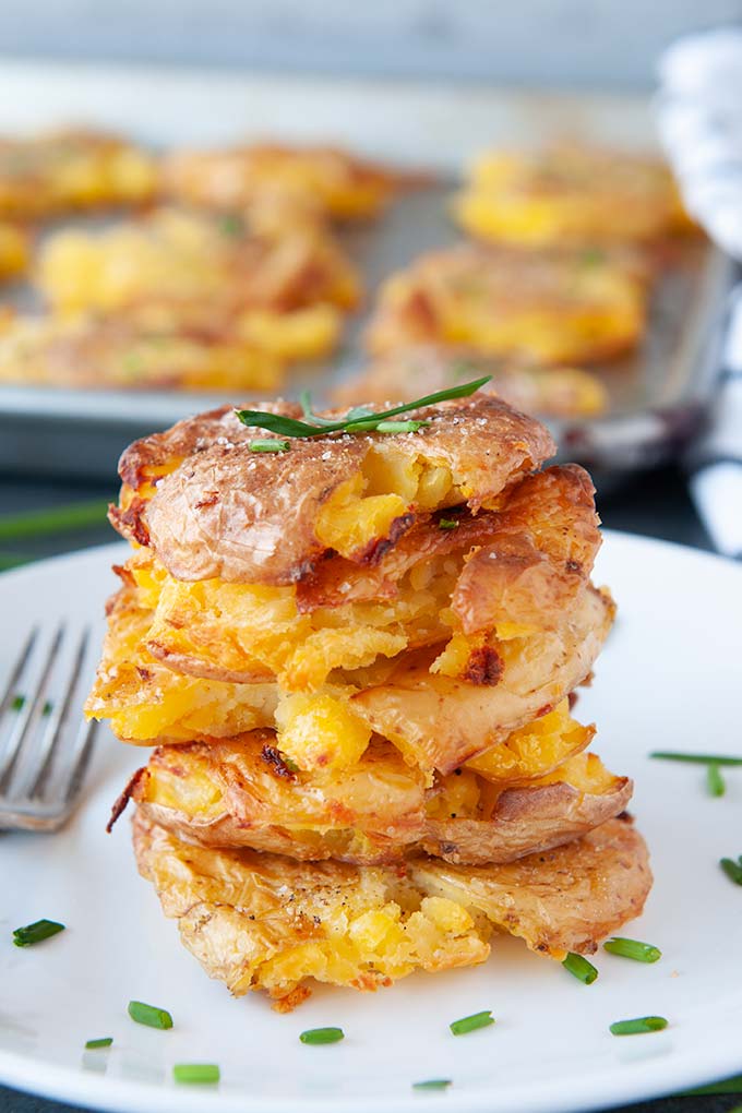 Stacked pile of salt and vinegar smashed potatoes topped with chives