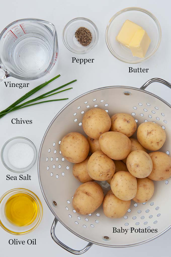 All the ingredients to make salt and vinegar smashed potatoes such as butter, baby potatoes, and vinegar