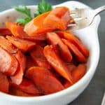 A forkful of brown sugar carrots above a bowl of carrots