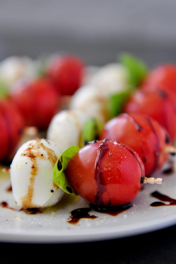 Caprese salad skewers drizzled with balsamic glaze, salt, and pepper