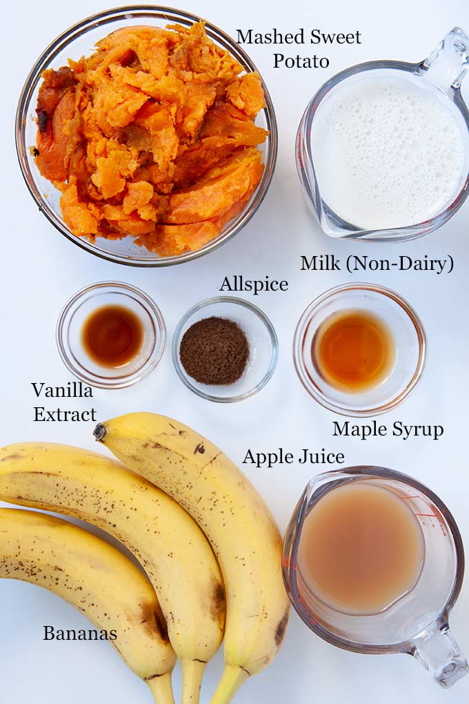 All of the ingredients to make  mashed sweet potatoes such as non-dairy milk, baked sweet potatoes, maple syrup, apple juice, and the secret ingredient...bananas.