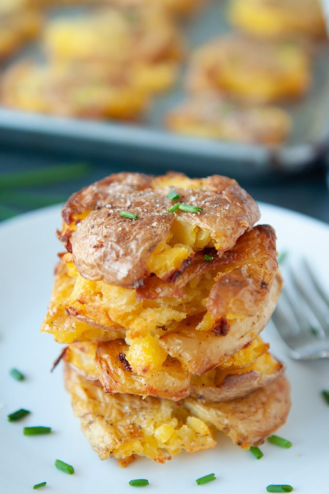 Stacked pile of salt and vinegar smashed potatoes topped with chives
