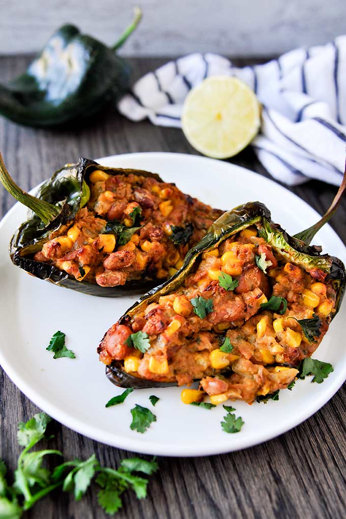 Up close plated poblano peppers sprinkled with cilantro and stuffed with pinto beans, cheese, and corn.  