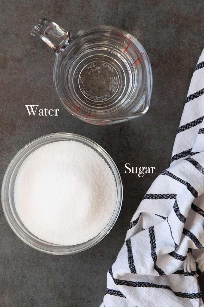Measuring cup full of water and a cup of sugar are the ingredients to make the simple syrup.