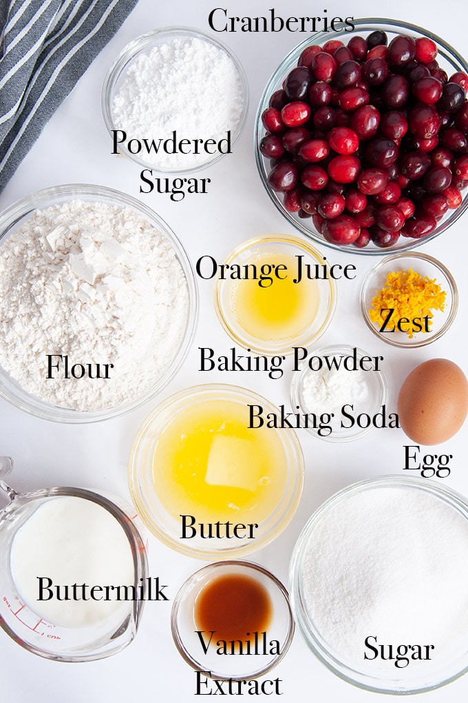 All of the ingredients to make cranberry bread including fresh cranberries, orange zest, melted butter, buttermilk, and vanilla extract.