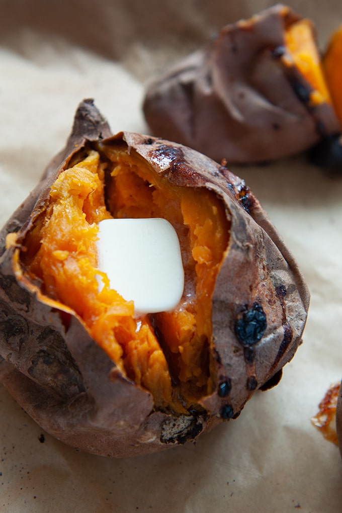 A baked sweet potato split open with a pat of butter.