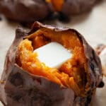 Baked sweet potato that's split open with a pat of butter