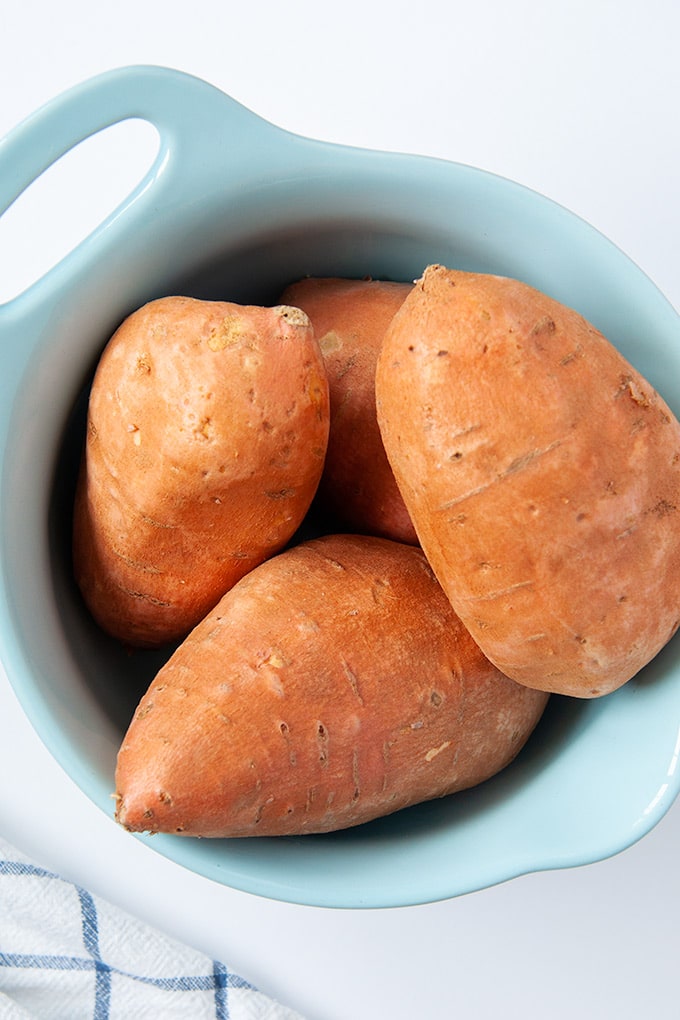 Light blue bowl of uncooked sweet potatoes.