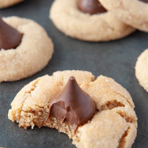Up close peanut blossom cookie with a bite taken out of it and more cookies in the background