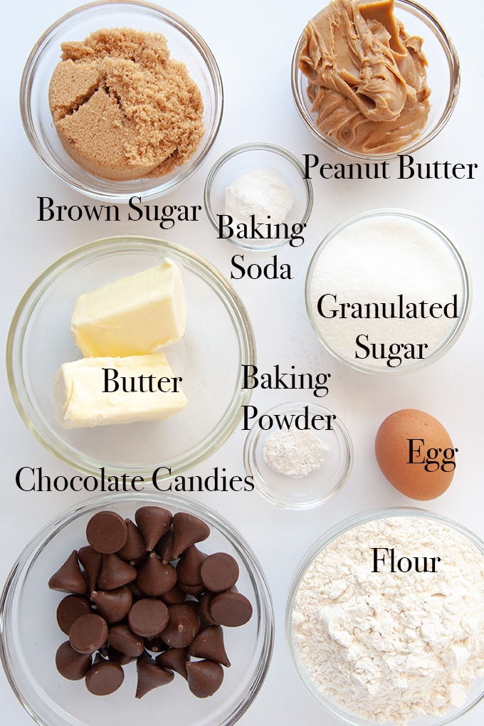 All of the ingredients to make peanut blossom cookies such as butter, egg, peanut butter, brown sugar, and chocolate kisses 