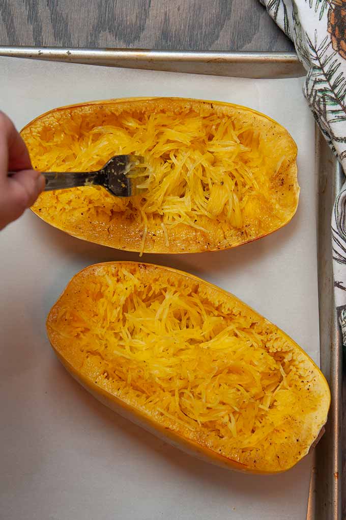 Cooked spaghetti squash being pulled into strands with a fork
