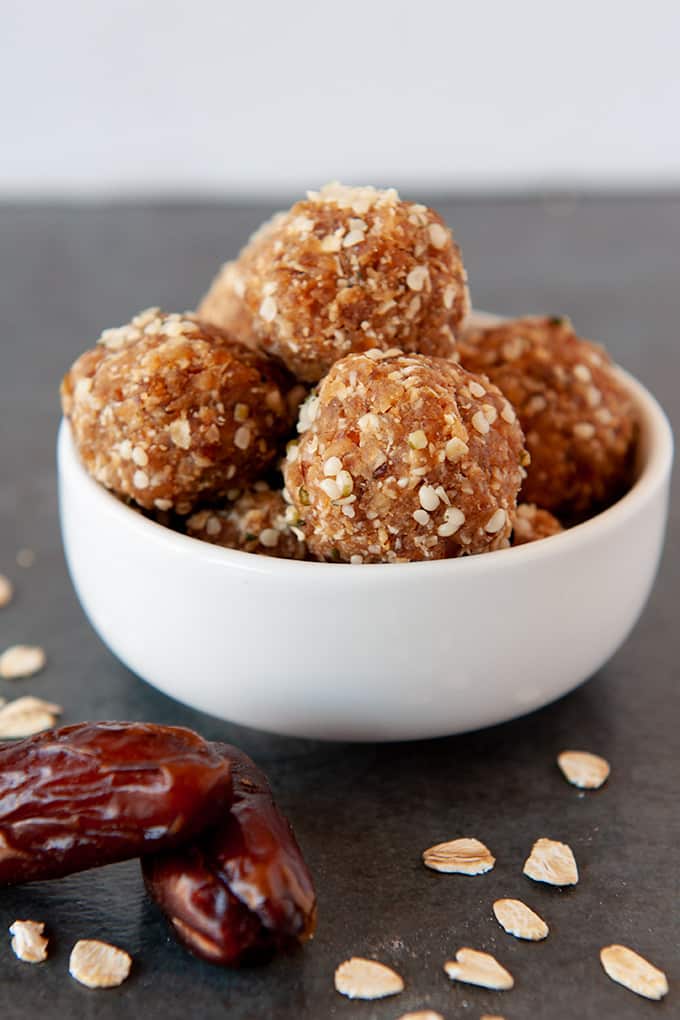 A small white bowl of energy balls with dates in foreground.