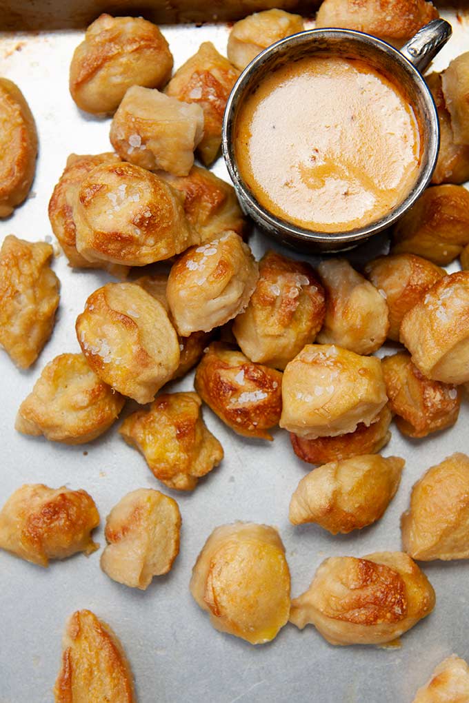 Up close salted pretzel bites with metal cup of hot beer cheese dip