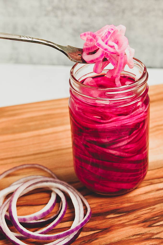 A jar of pickled onions with a fork full of onions.