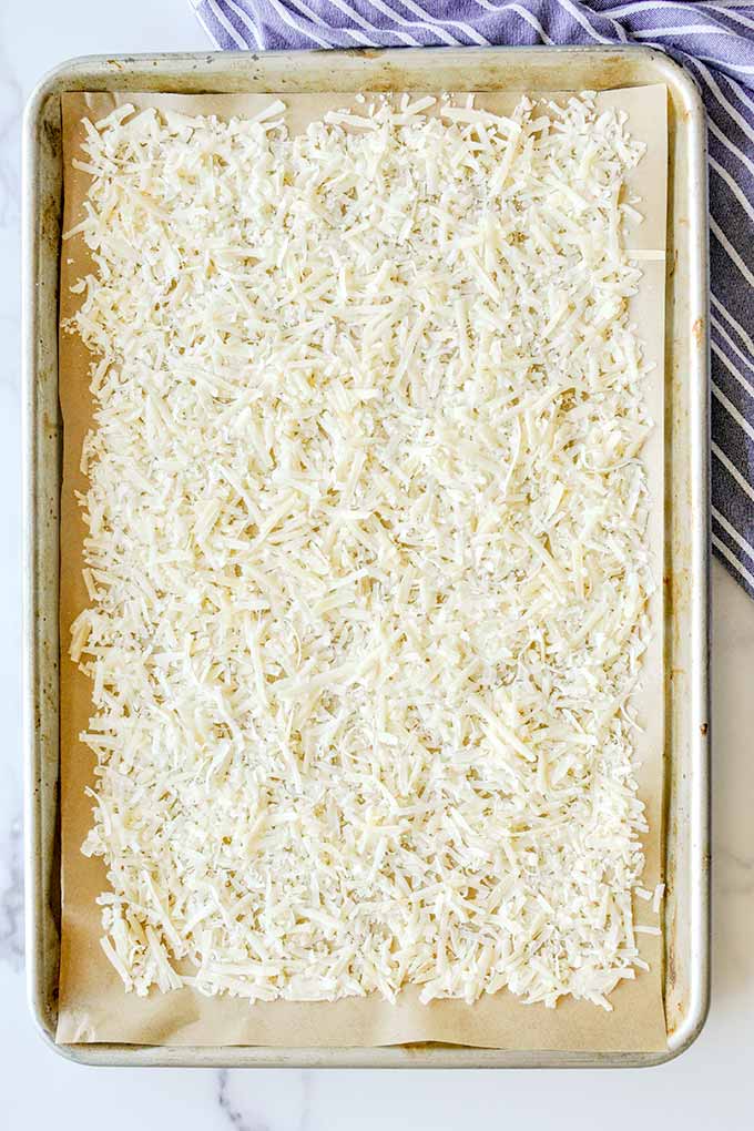 A baking sheet with a thin layer of parmesan cheese.