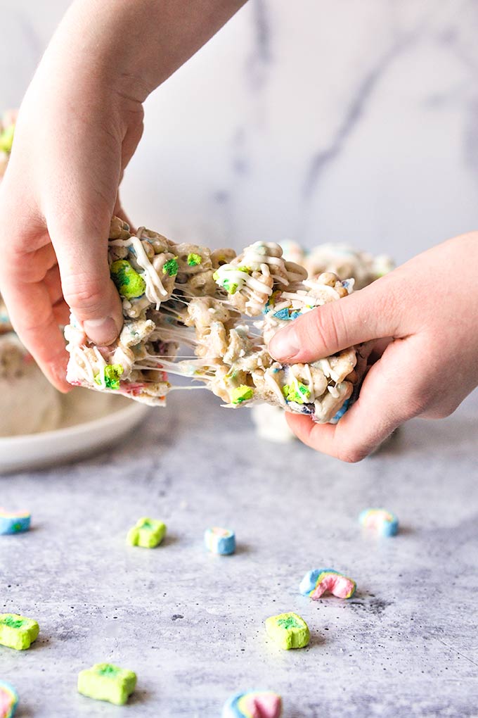 Lucky Charms treat being pulled apart with gooey marshmallow strings.