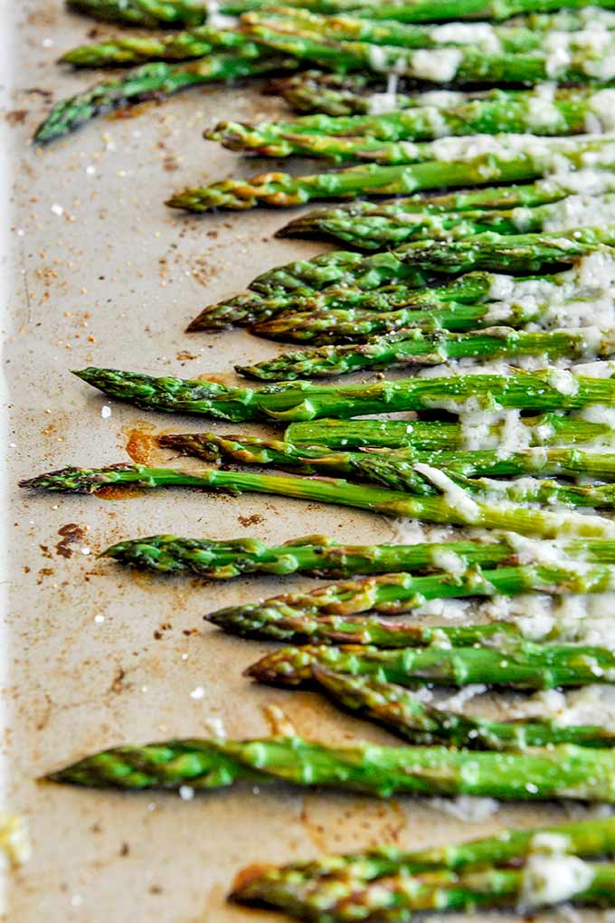 Above shot of a baking tray with roasted asparagus that is all lined up. 