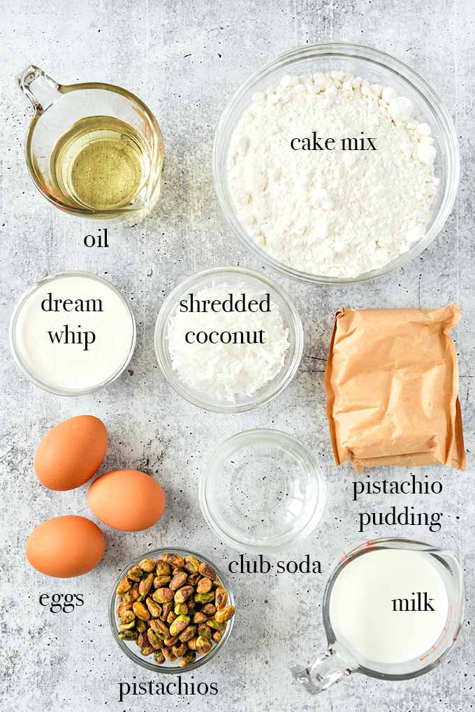 All of the ingredients to make Watergate cake such as pistachio pudding, cake mix, eggs, dream whip, milk and pistachios.
