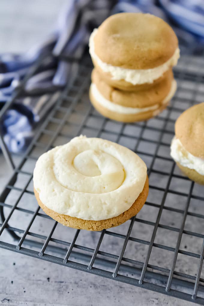 A swirl of frosting on one half of a cookie on a cooling rack with other fluffernutter in background.