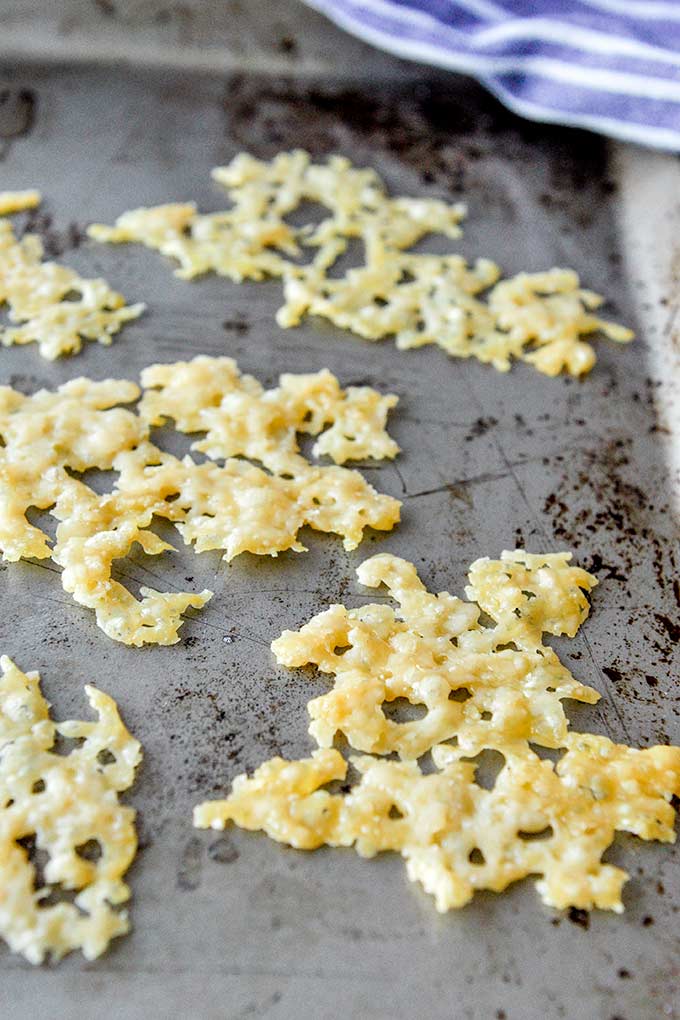 A baking sheet with broken pieces of cheese crisps.