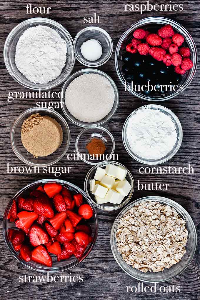 All of the ingredients needed to make berry crisp like brown sugar, butter, cinnamon, oats, and berries.