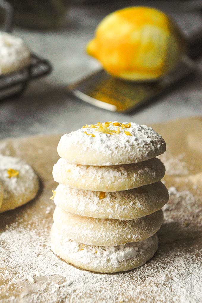A tall stack of cookies dusted with powdered sugar and topped with zest.