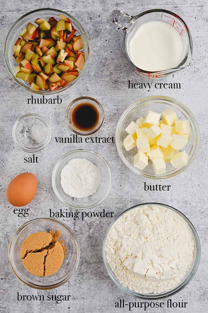 All of the ingredients to make rhubarb  scones such as brown sugar, butter, heavy cream, and rhubarb.
