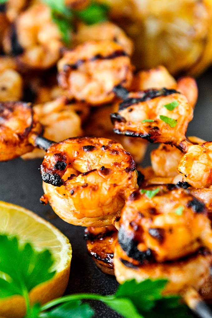 Grilled shrimp on skewers with lemon slices and parsley.