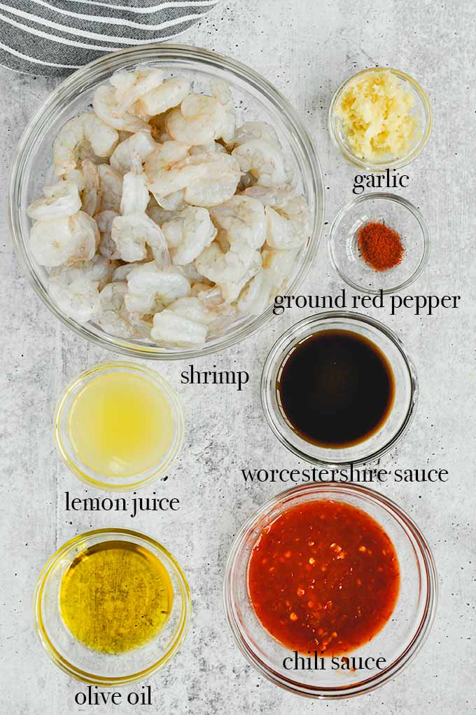 All of the ingredients needed to make spicy shrimp like ground red pepper, chili sauce, garlic, and lemon juice.