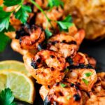 Grilled shrimp on skewers with lemon slices and parsley.