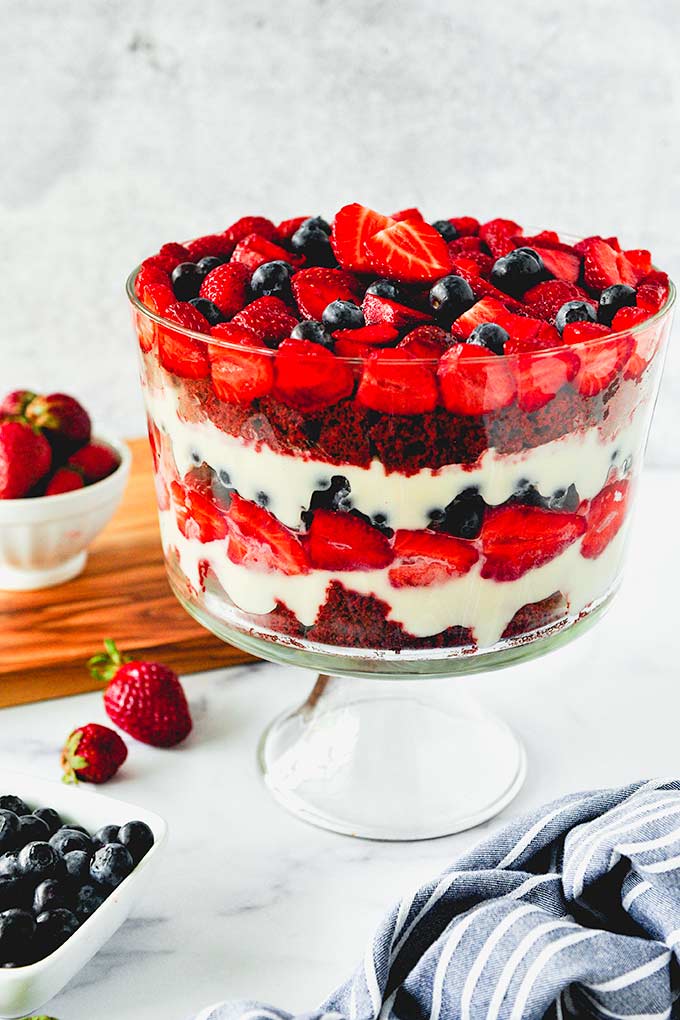 Whole assembled trifle with strawberries and blueberries around.