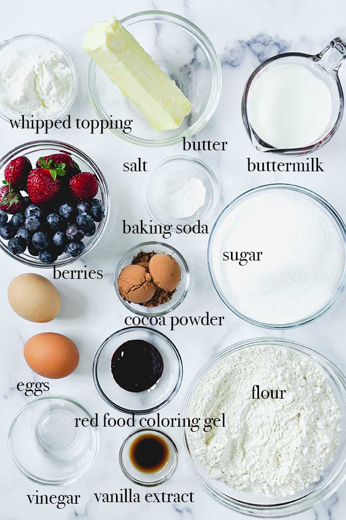 All of the ingredients needed to make trifle like red food coloring, cocoa powder, fresh berries, and buttermilk