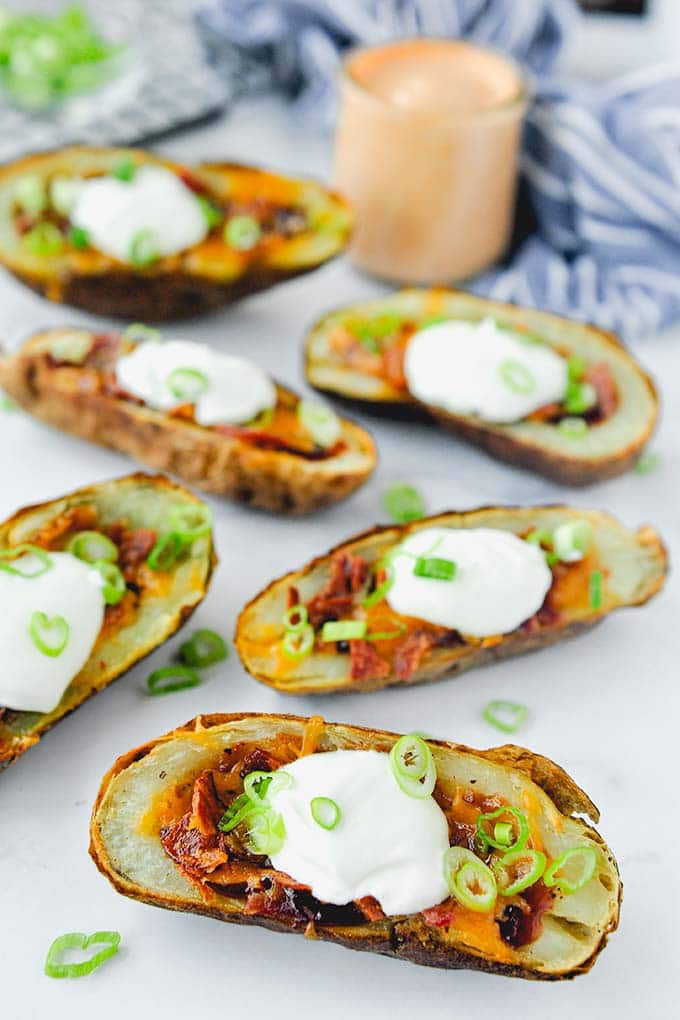 Air fryer potato skins laid out with a jar of chipotle mayo in the background.