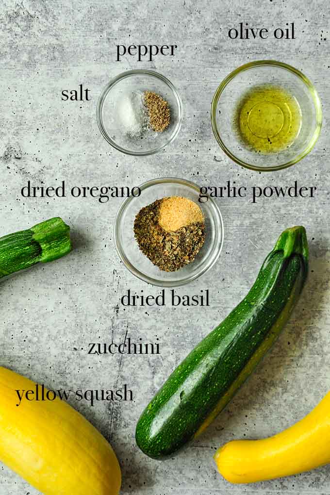 All of the ingredients needed to make air fryer squash such as olive oil, garlic powder, zucchini, and yellow squash.