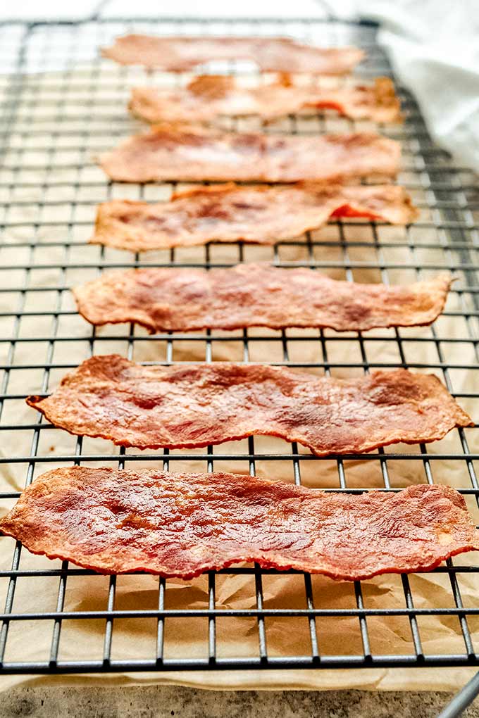 A cooling rack of lined up crispy turkey bacon.