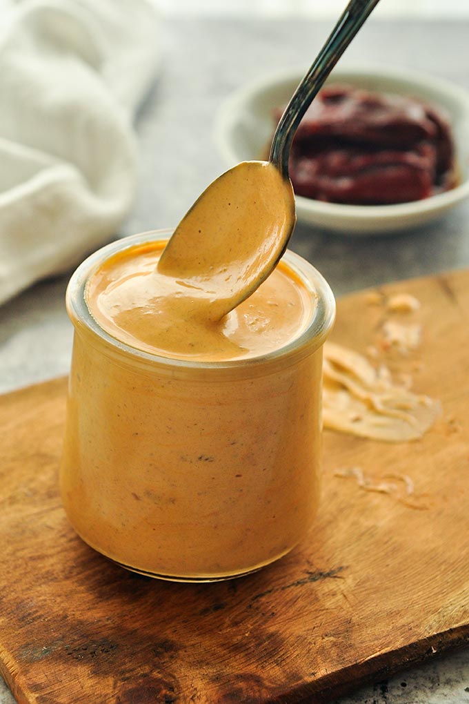 A small jar of chipotle mayonnaise  with a spoon about to take a scoop.