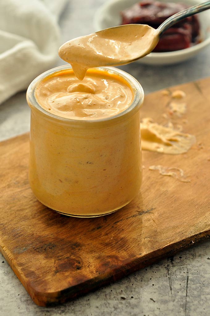 A small jar of chipotle mayonnaise with a spoon taking a big scoop.
