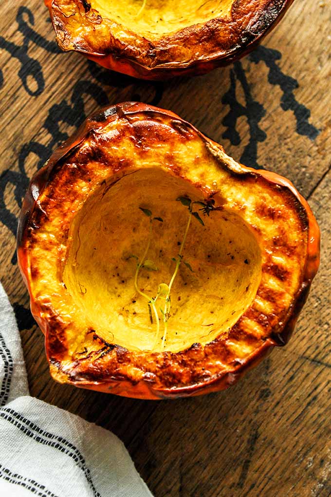 An above view of an acorn squash with a thyme sprig.