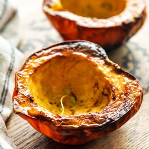 Two halves of air fryer acorn squash with a sprig of thyme.