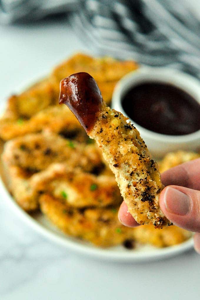 Up close of one chicken tender that has been dipped into bbq sauce.