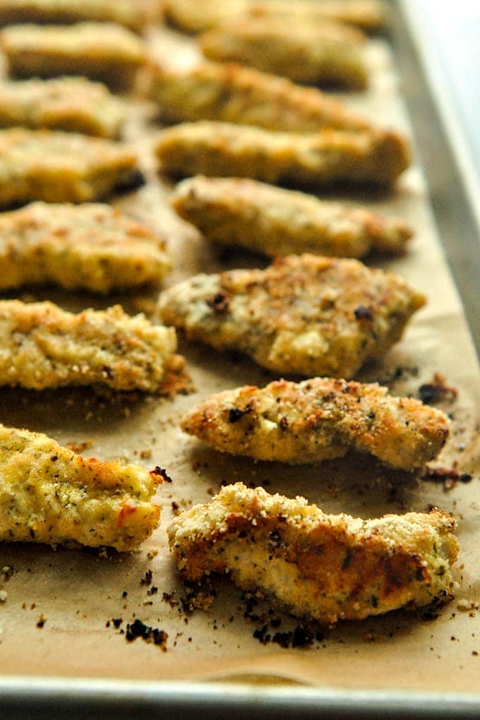 A front view of a baking sheet full of chicken tenders.