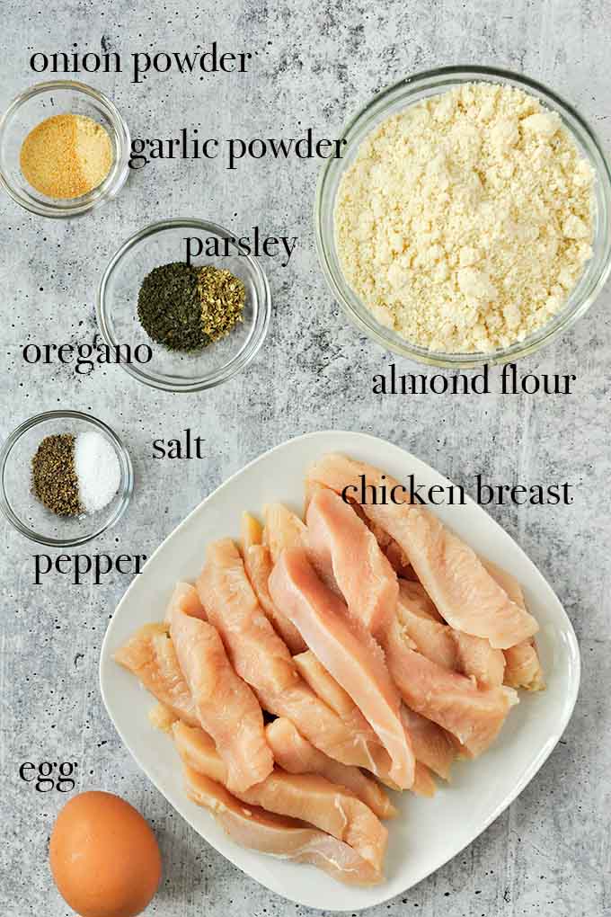 All of the ingredients needed for gluten free chicken tenders such as almond flour, chicken breasts, egg, and garlic powder.