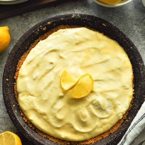 A lemon freeze pie with lemon on top, a bowl of lemons, and a striped towel.