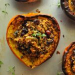 Above view of a baked acorn squash stuffed and topped with a sprig of thyme.