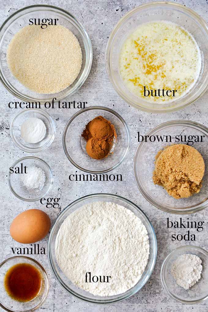 All of the ingredients needed for snickerdoodle bars such as melted butter, brown sugar, cinnamon, cream of tartar, and flour.